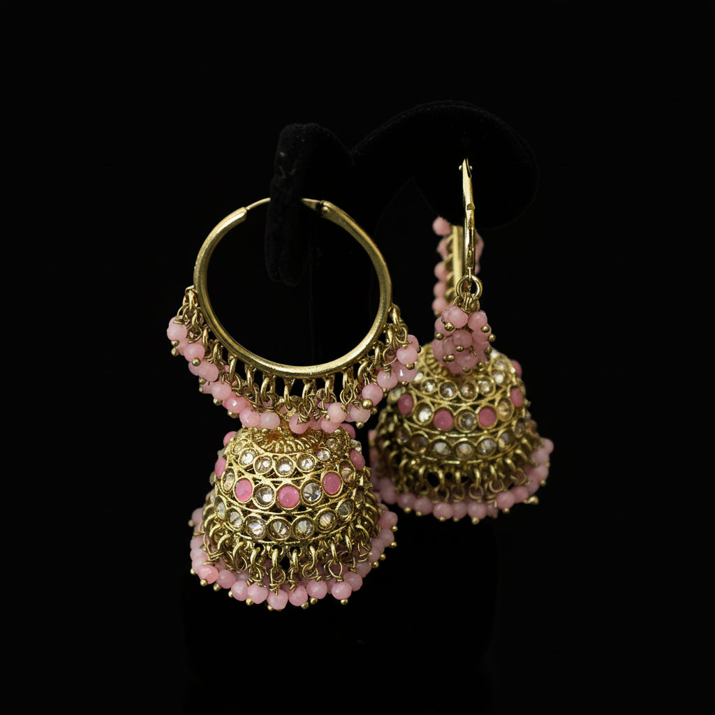 Gold and pink earrings on a black stand with 'Saheli' branding.