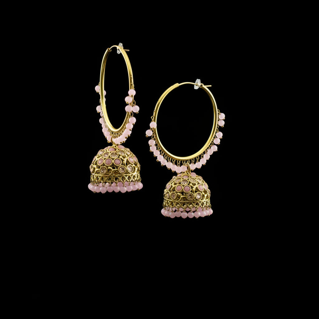 Gold hoop earrings with pink beads on a black stand against a gray background