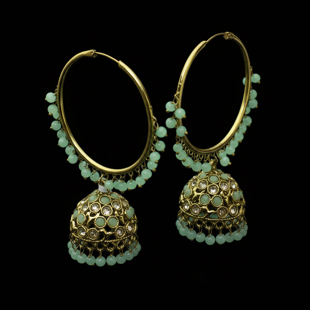 Gold and green beaded earrings on a black stand with 'SAHELI' branding.