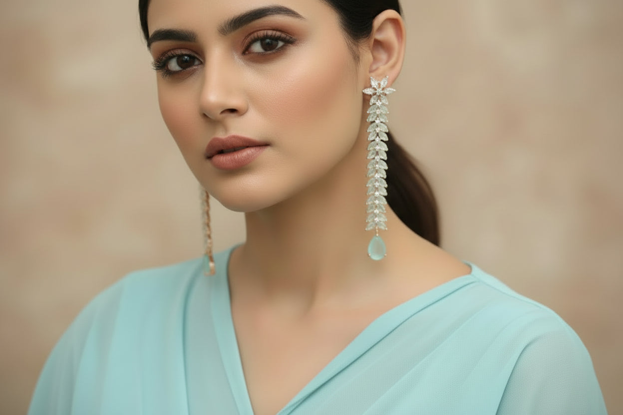 Pair of long earrings with floral designs and turquoise stones on a dark background