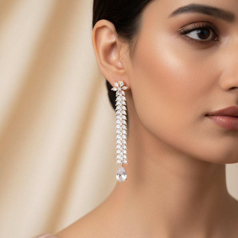 Pair of long, leaf-like earrings with teardrop-shaped stones on a dark background