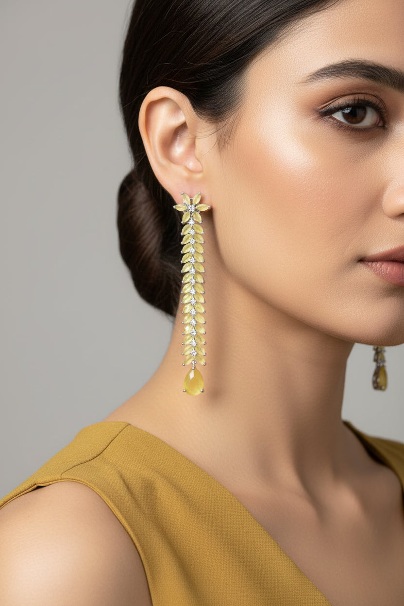 Pair of long, leaf-shaped earrings with a central gemstone on a dark background