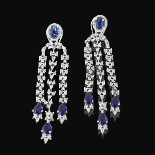 Pair of earrings with blue gemstones and diamond-like stones on a black background
