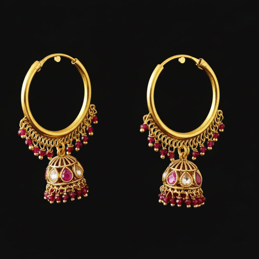 Gold hoop earrings with red gemstones on a black background, branded 'Saheli'.
