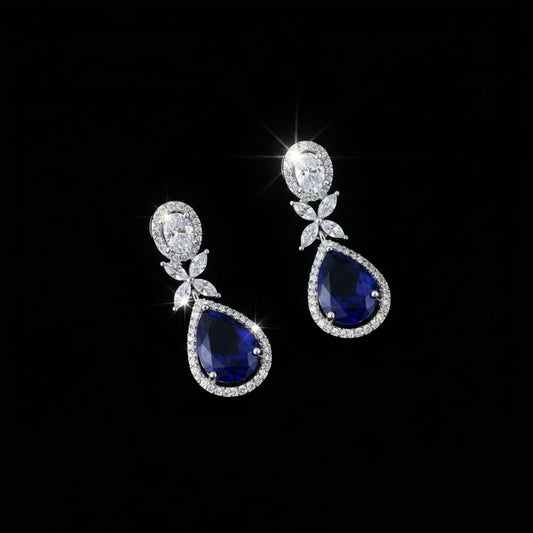 Pair of teardrop-shaped earrings with purple gemstones on a dark background