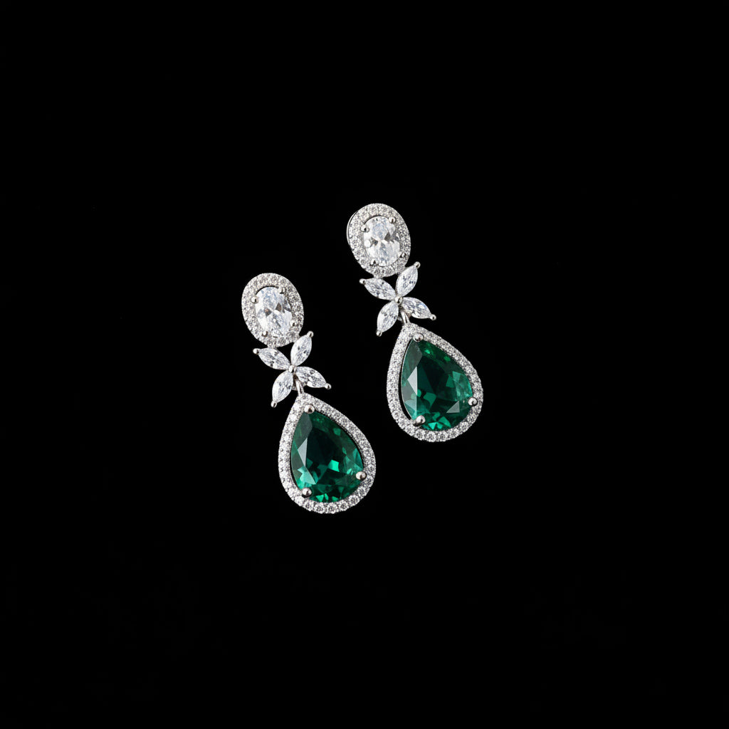 Pair of green teardrop earrings with silver accents on a dark background