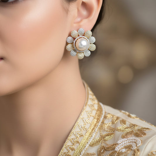 Pair of gold and pearl earrings on a dark background