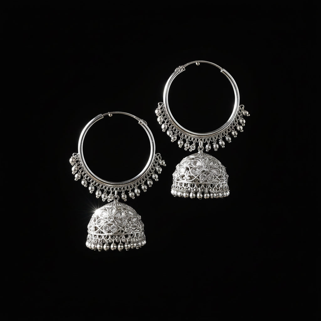 Silver hoop earrings with dangling parts on a black stand, branded 'Saheli'.