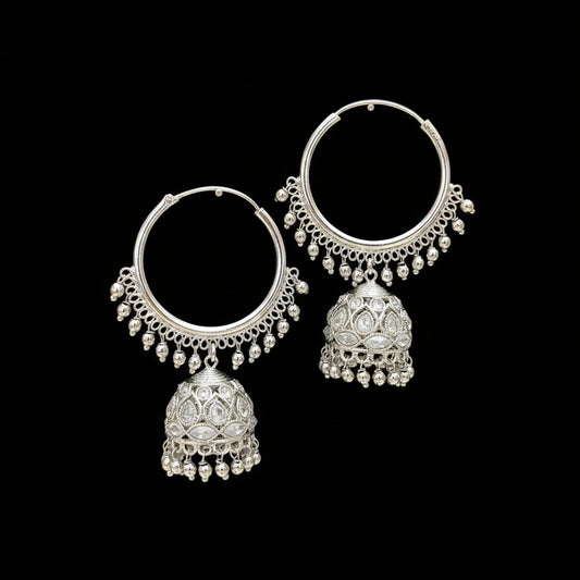Silver hoop earrings with jhumkas on black stands against a gray background, branded 'Saheli'.
