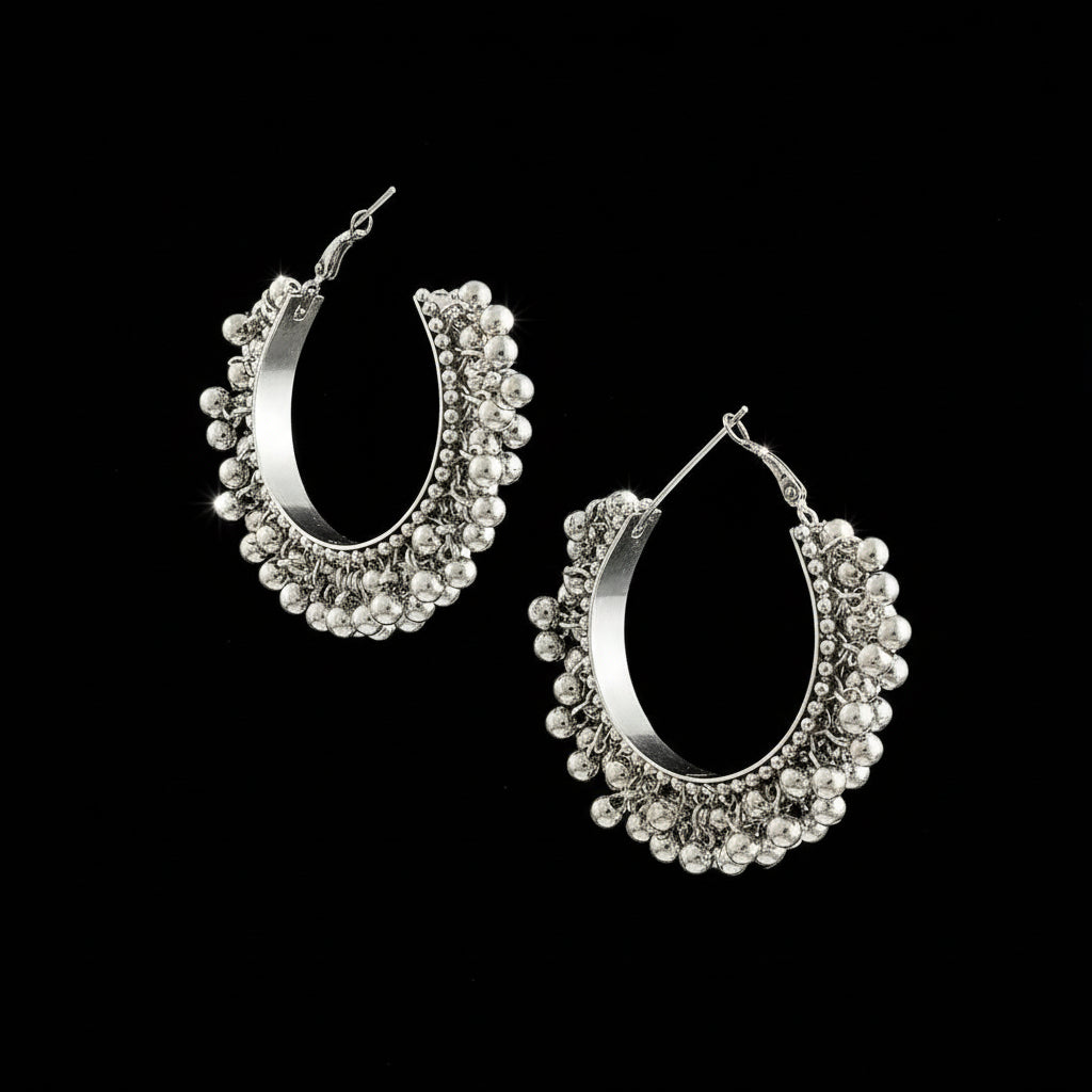 Silver hoop earrings with beaded details on a gray background, featuring the brand 'Saheli'.