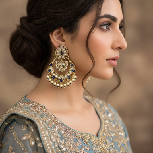Pair of ornate earrings with gold, blue, and pearl details on a dark background