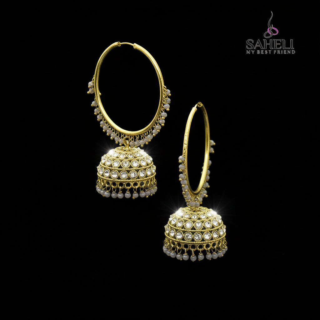 Gold hoop earrings with spherical embellishments on a black stand, branded 'SAHELI'.