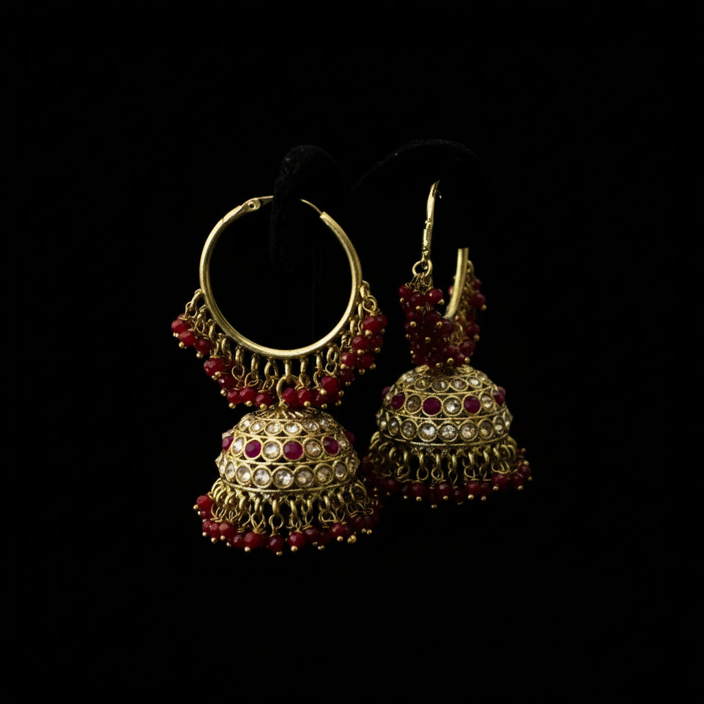 Gold and red beaded earrings on a black stand with a gray background