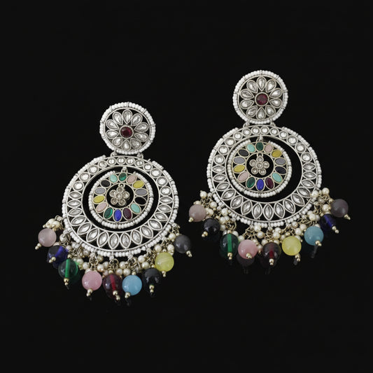 Ornate earrings with colorful beads on a dark background, featuring the brand 'Saheli'.