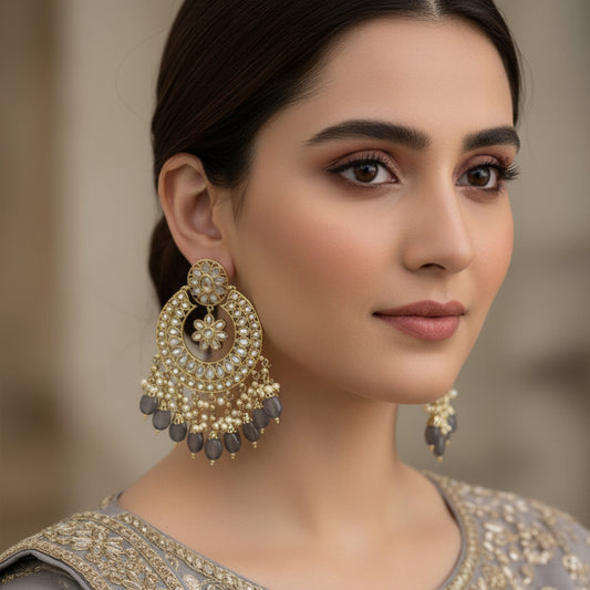 Ornate gold and black earrings with 'SAHELI' branding on a dark background