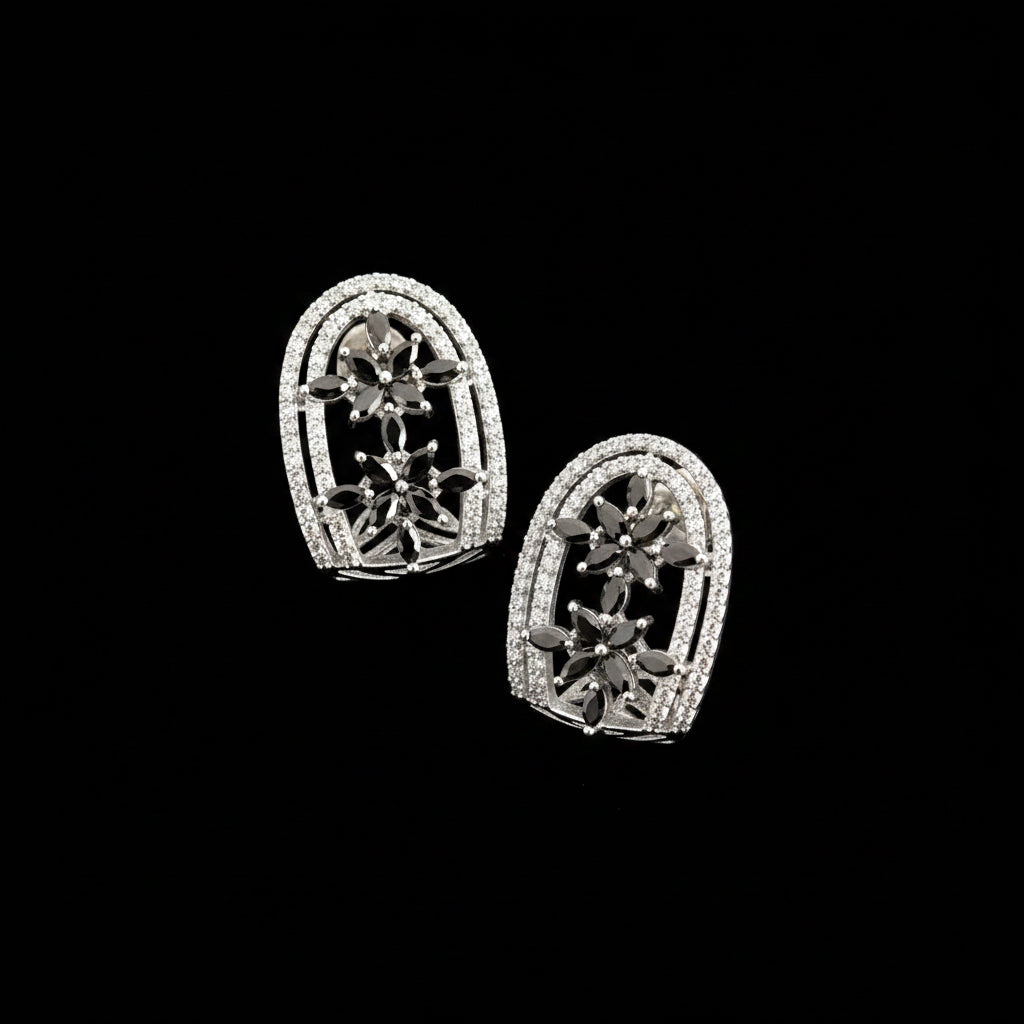 Pair of silver earrings with gemstones on a gray background, featuring the Saheli brand.