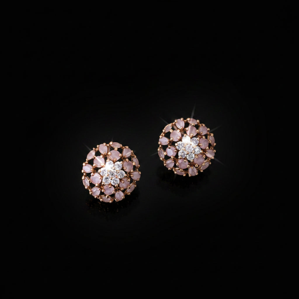 Pair of rose gold earrings with clear stones on a dark gray background, branded 'Saheli'.