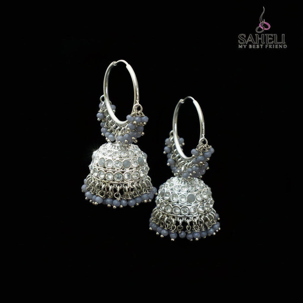 Silver hoop earrings with blue beads on a black stand against a gray background, branded 'Saheli'.