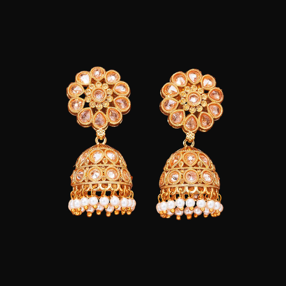 Gold and pearl earrings on a brown background