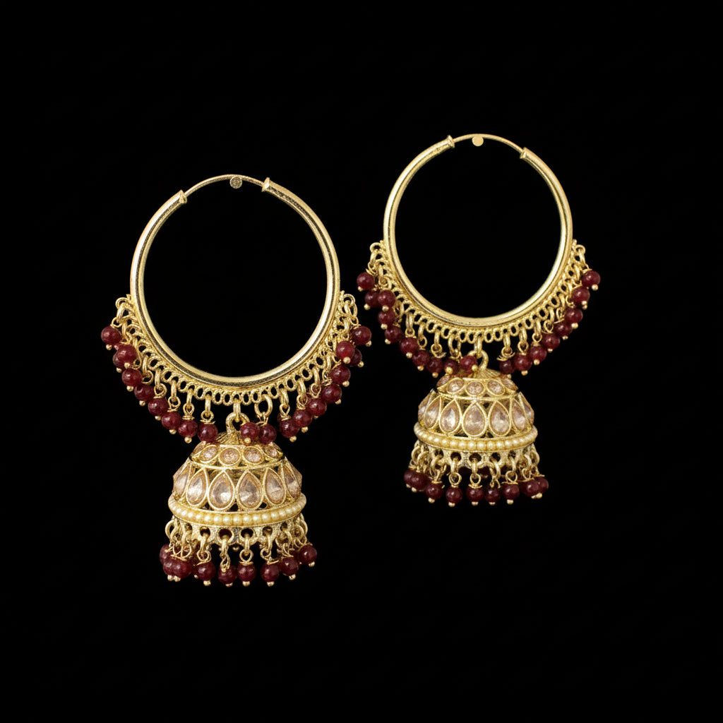 Gold and red beaded earrings on gray stands with 'Saheli' branding.