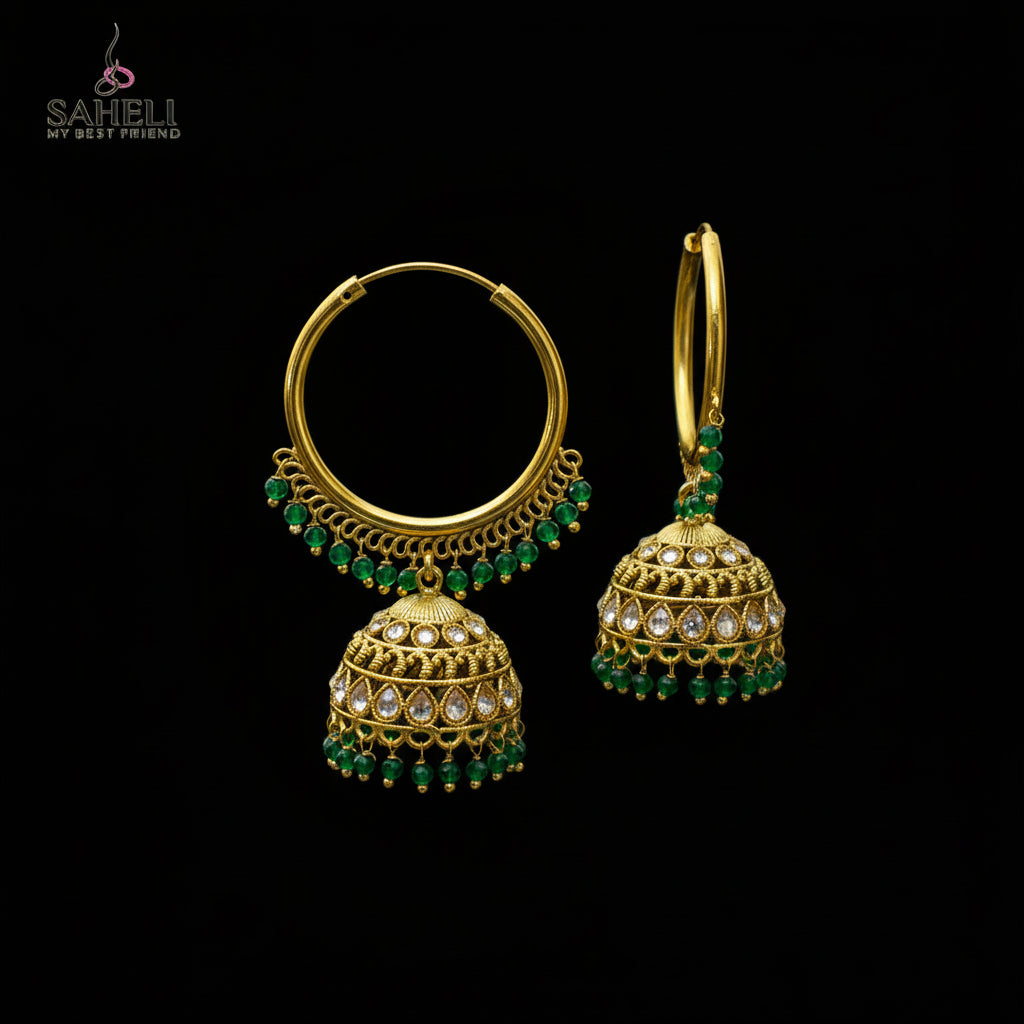 Gold hoop earrings with green gemstones on a black stand against a gray background
