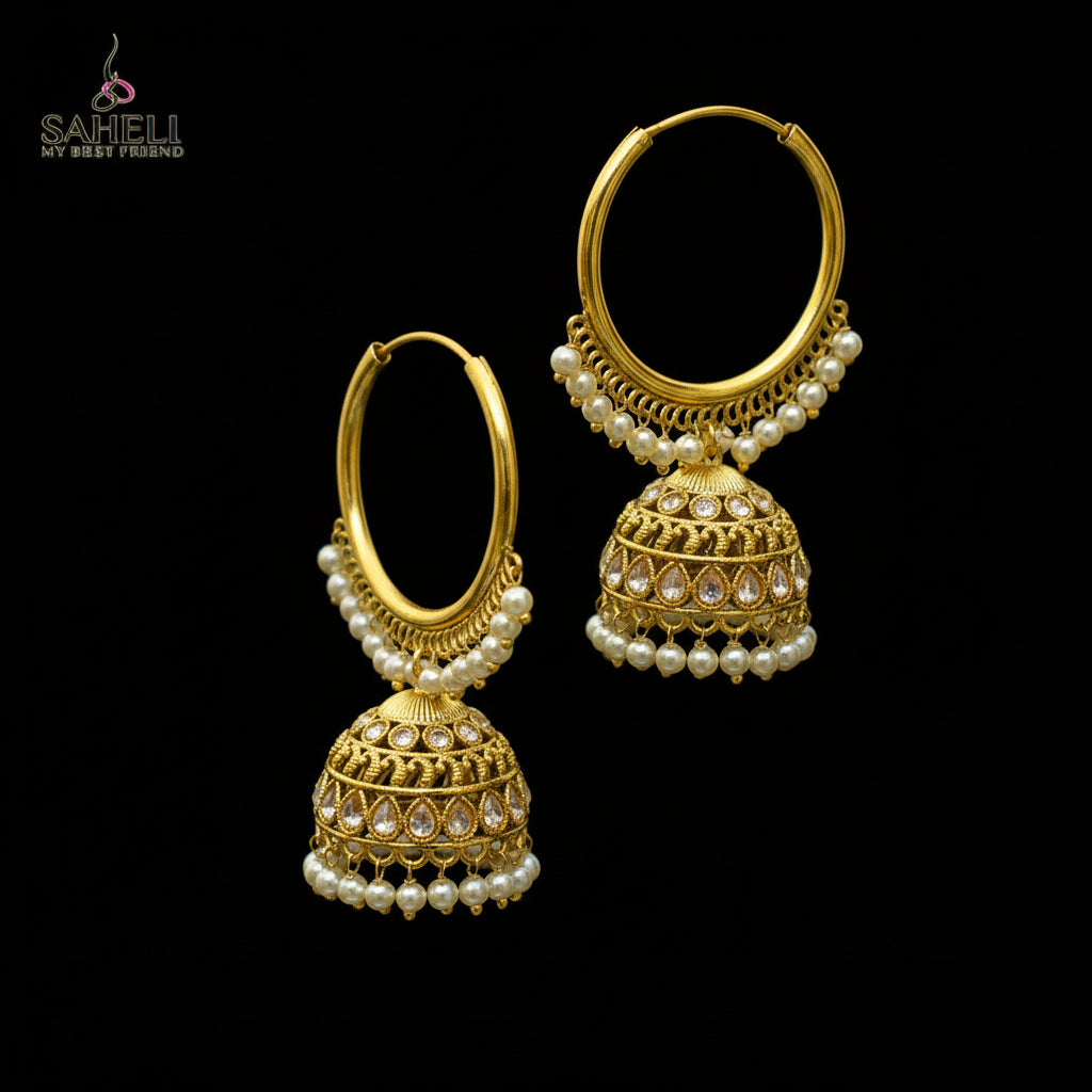 Gold earrings with pearl and gemstone details on a black stand against a gray background.