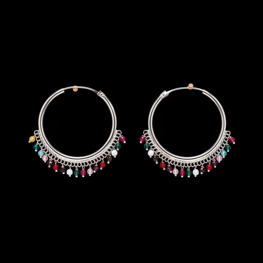 Pair of silver hoop earrings with colorful beads on a brown background