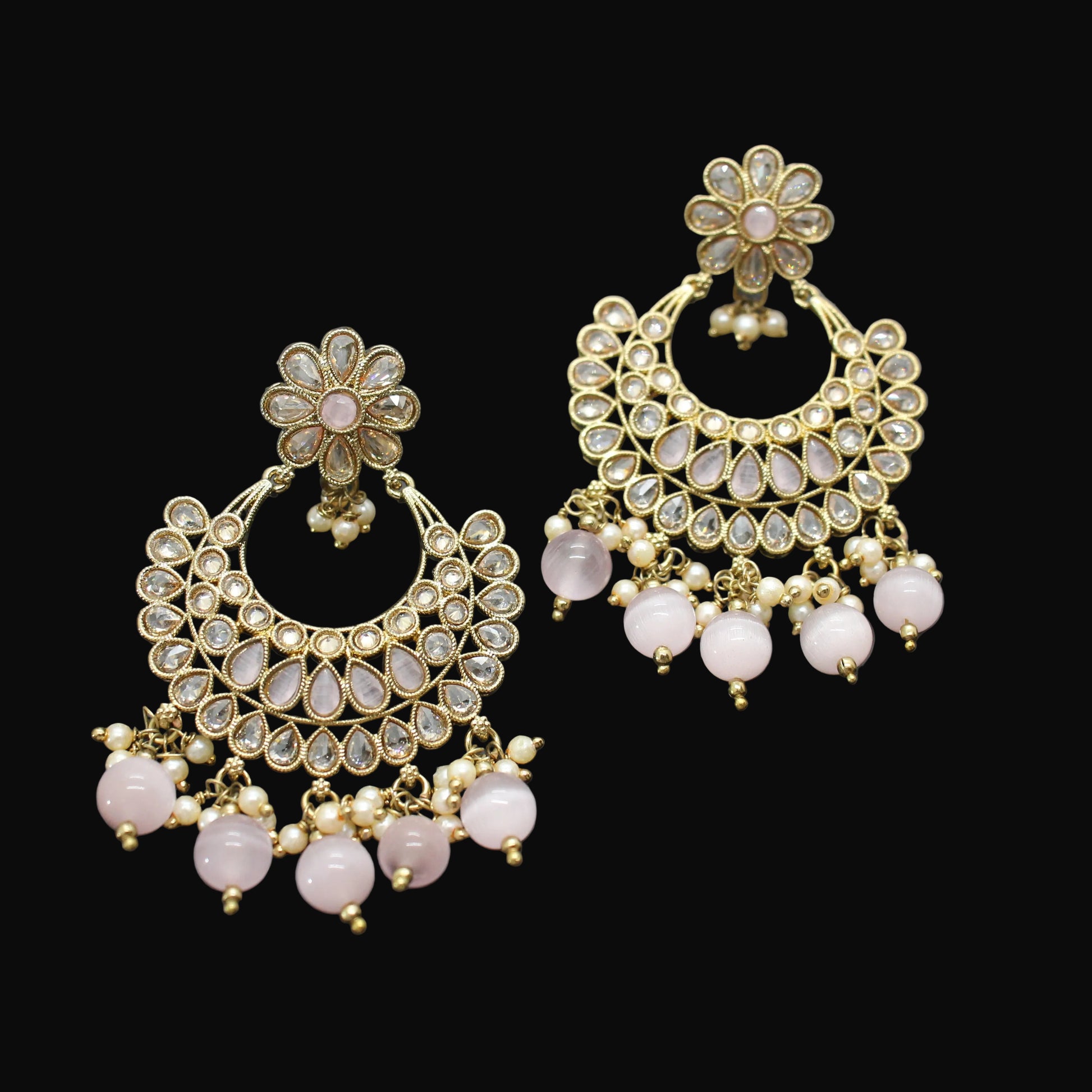 Pair of gold and pink earrings on a dark gray background