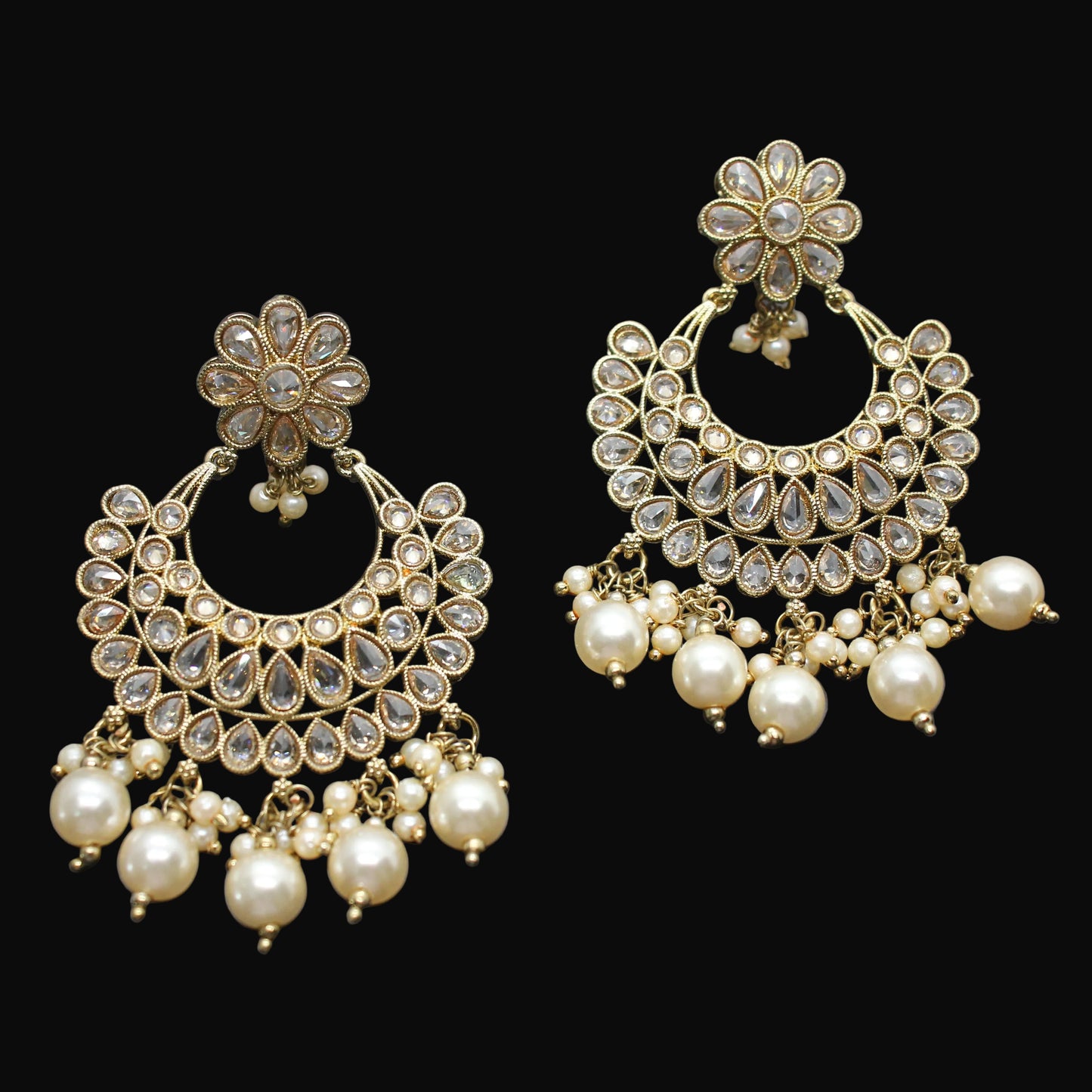 Pair of gold and pearl earrings on a dark background