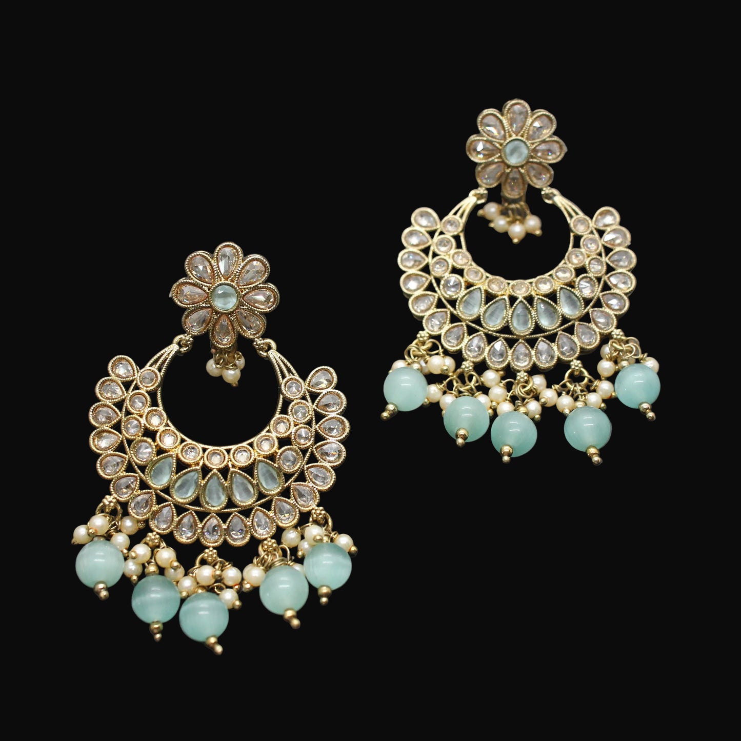 Pair of gold and turquoise earrings on a dark gray background