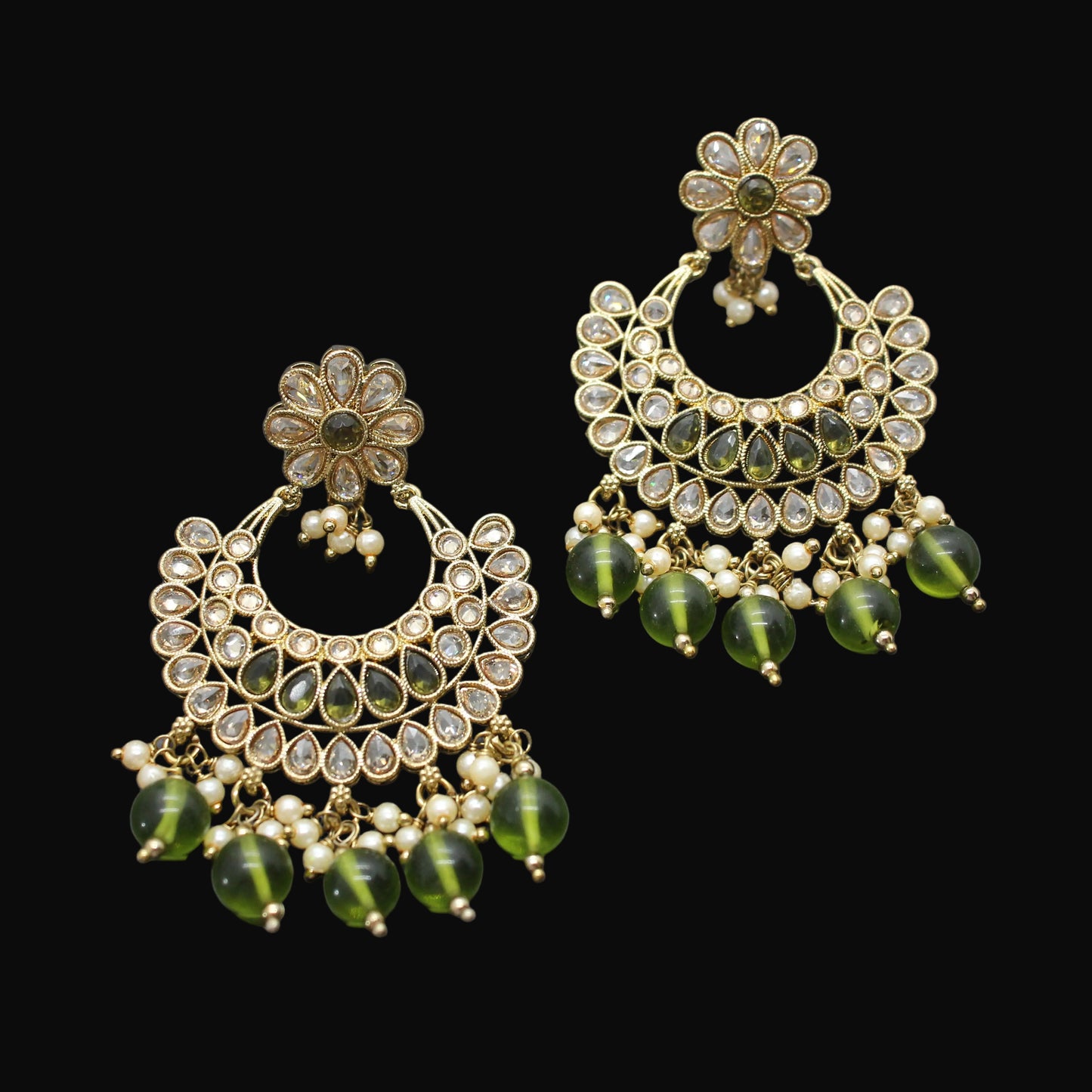 Pair of gold and green earrings on a dark gray background