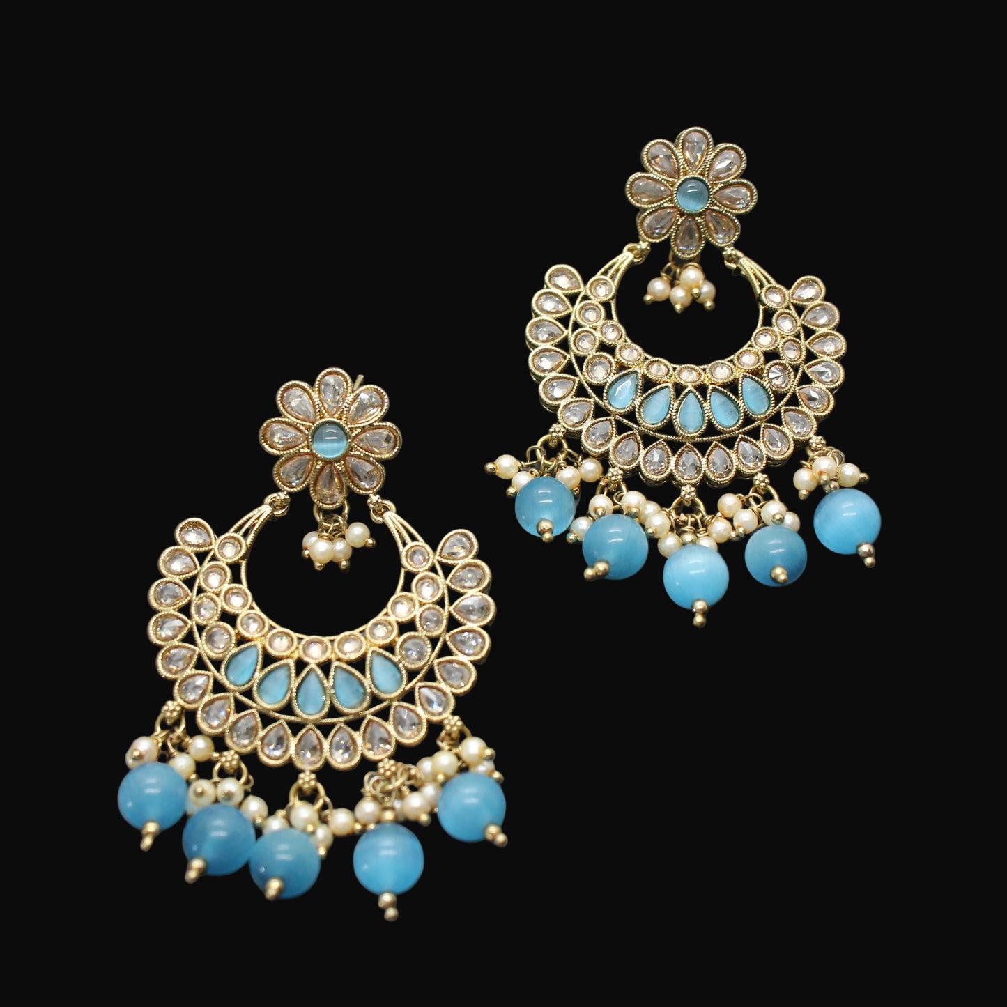 Pair of gold and turquoise earrings on a dark gray background