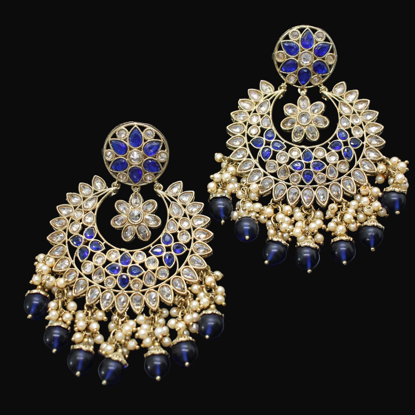 Ornate earrings with blue and gold details on a dark background