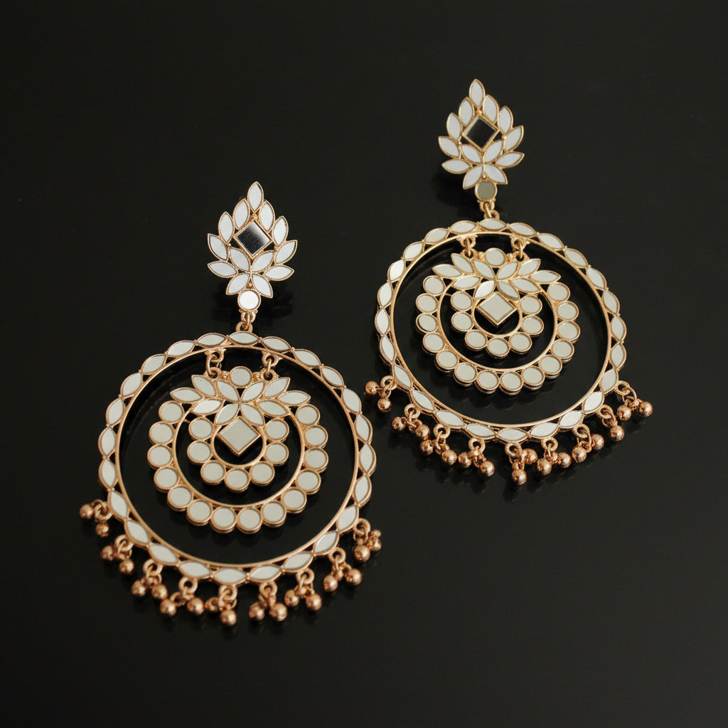 Pair of gold and pearl earrings on a dark background with 'Saheli' branding.