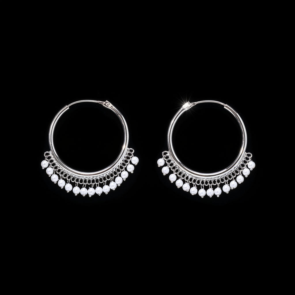 Pair of silver hoop earrings with pearl-like beads on a brown background