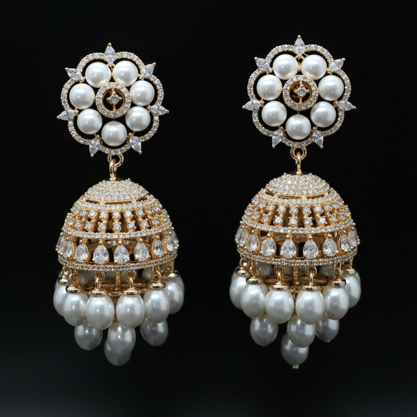 Pair of ornate earrings with pearls and gold accents on a black background