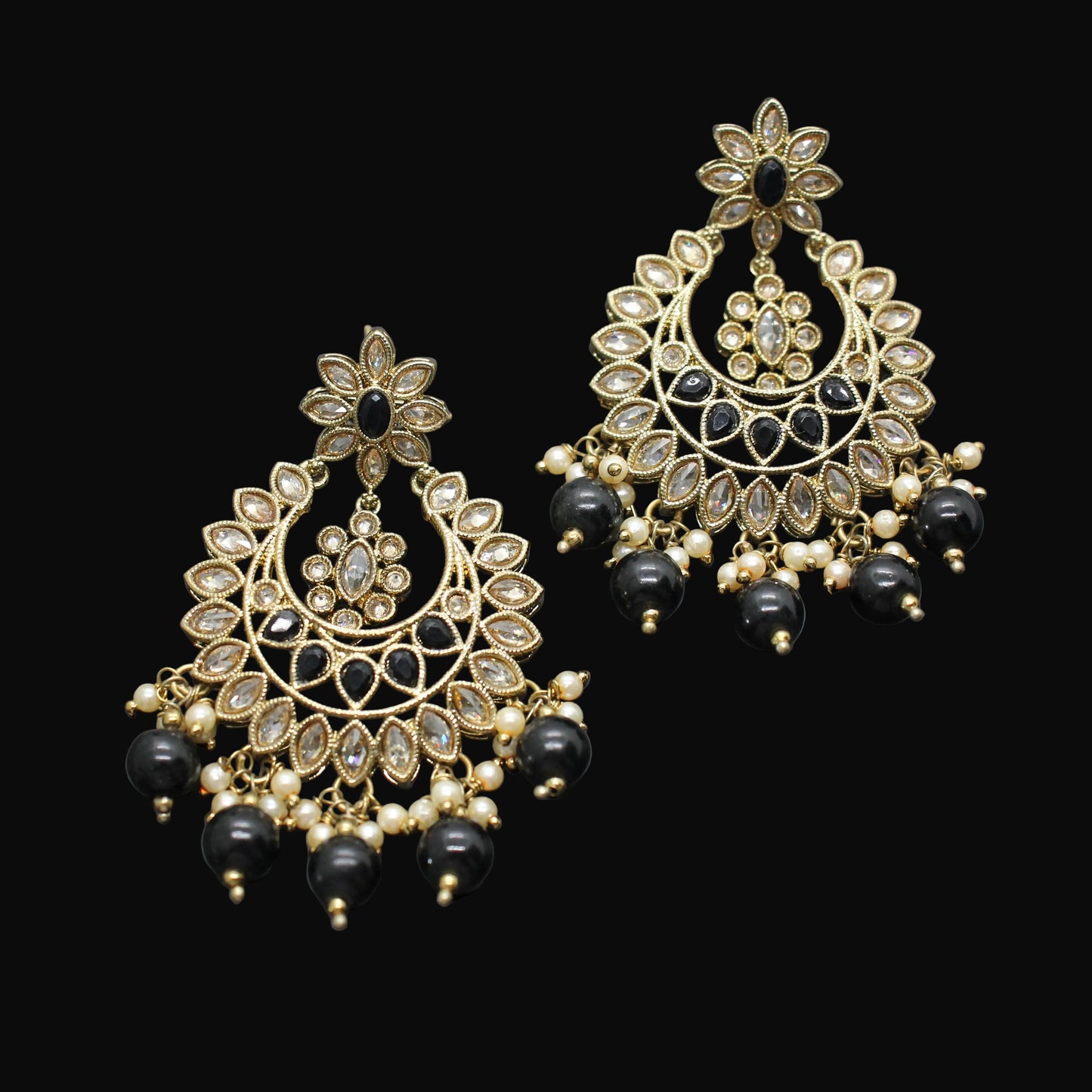 Pair of gold and black earrings on a dark gray background