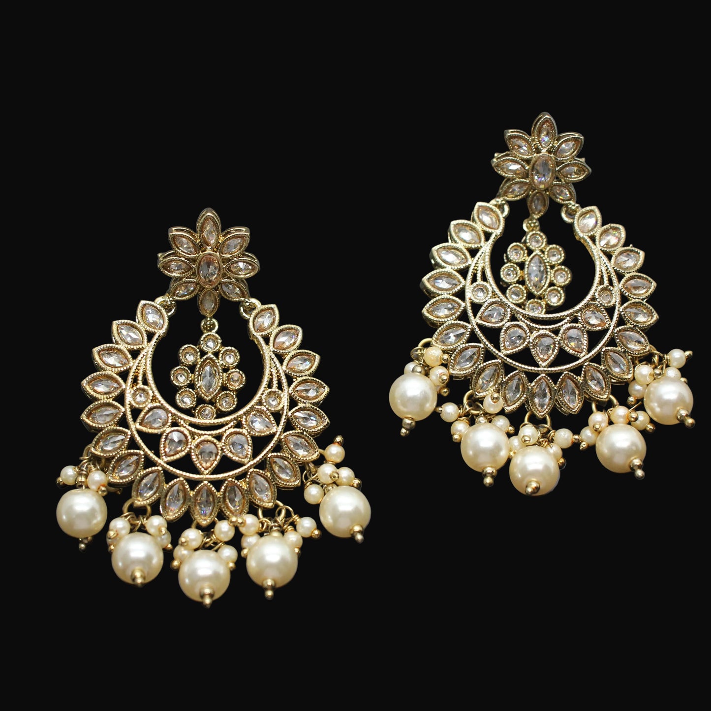 Pair of gold and pearl earrings on a dark gray background