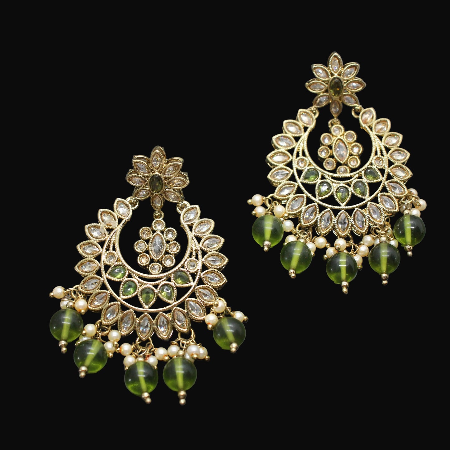 Pair of gold and green earrings on a dark gray background