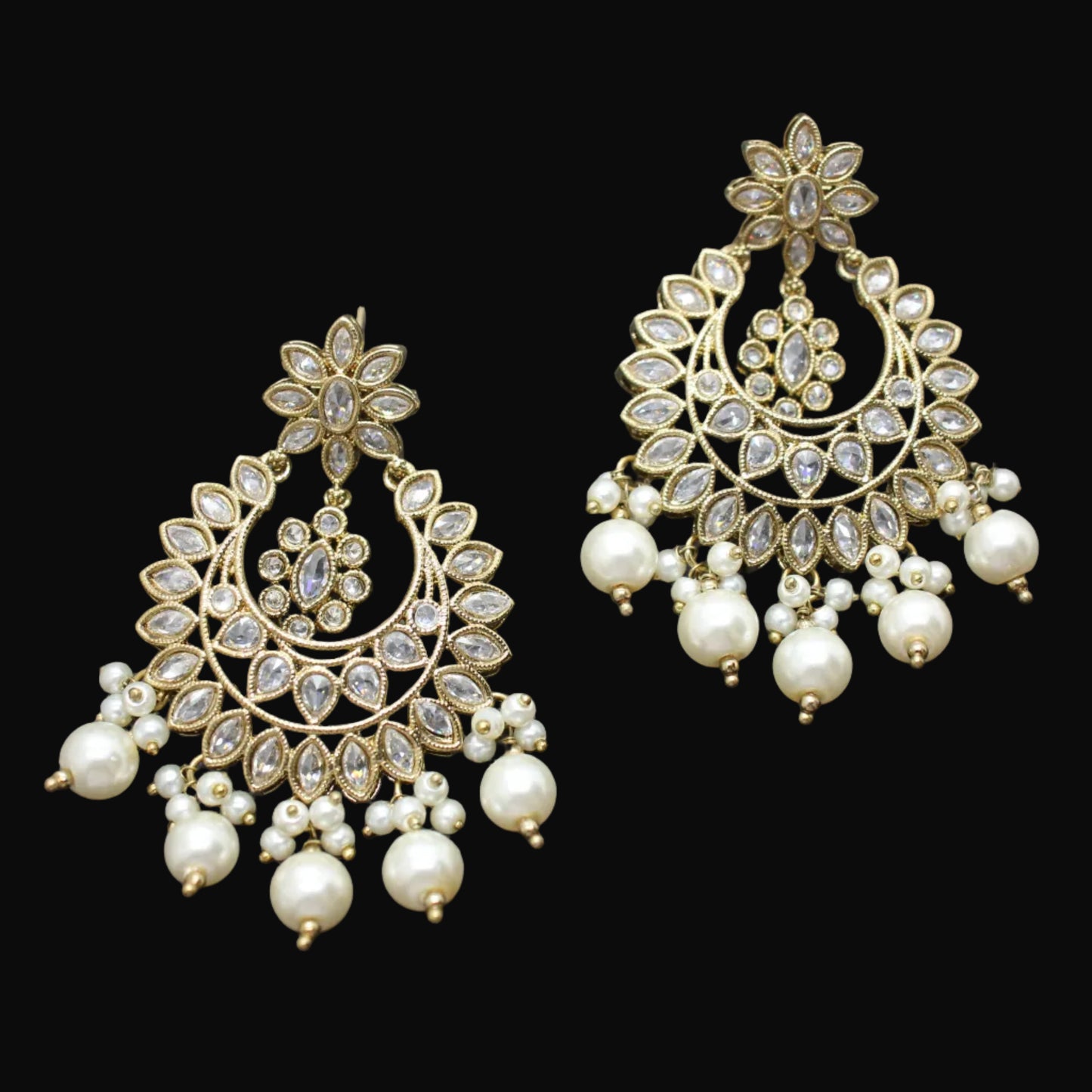 Pair of gold and pearl earrings on a dark gray background