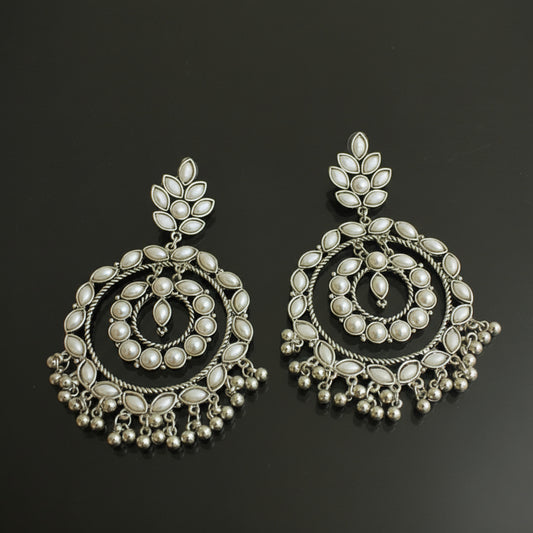 Pair of silver earrings with intricate designs on a black background