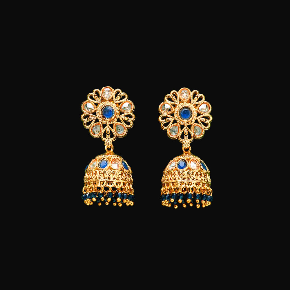 Gold earrings with blue stones on a green background