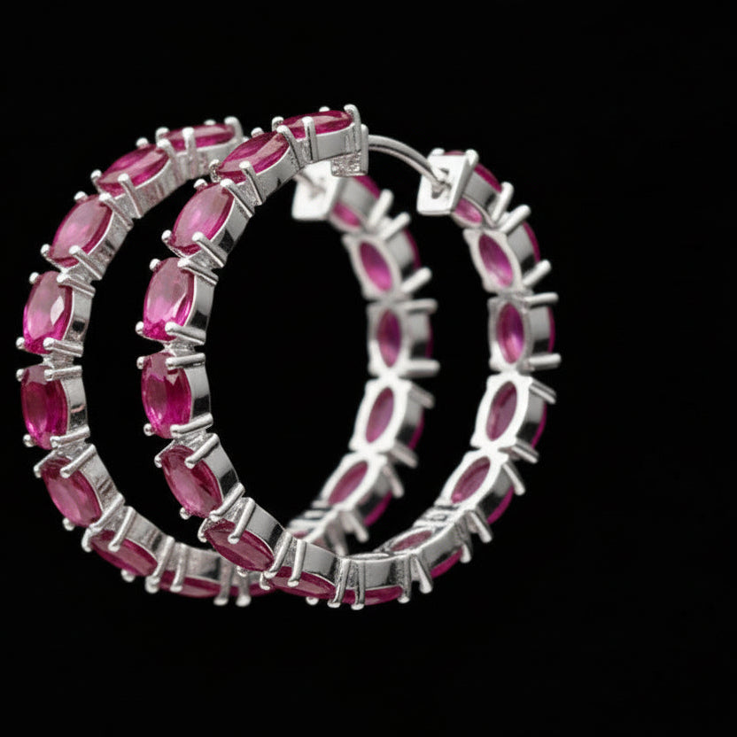 Gold hoop earrings with pink gemstones on a black background