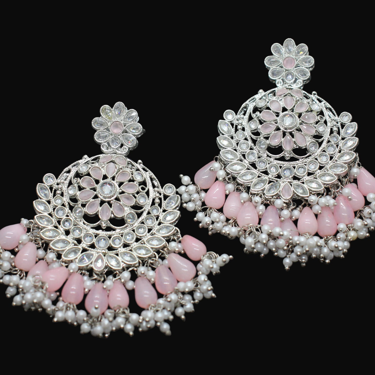 Pair of ornate earrings with pink stones on a dark background