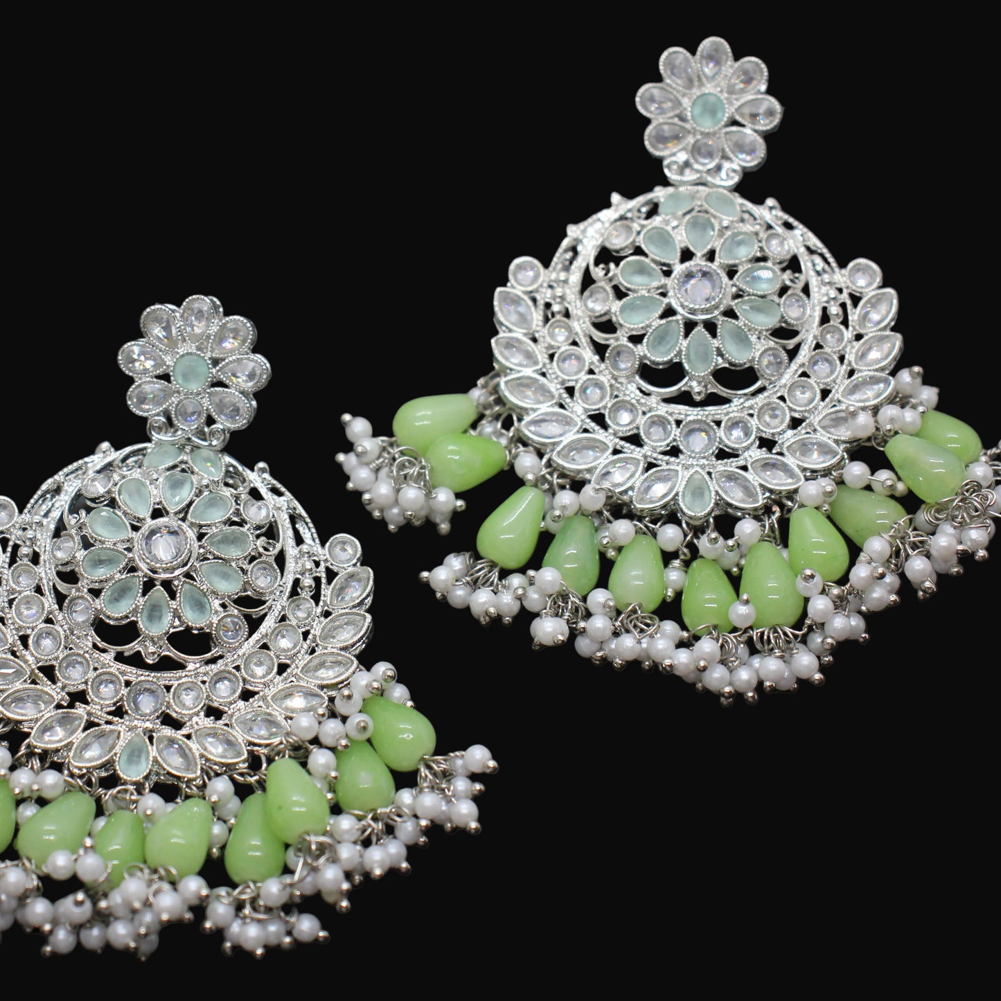 Pair of silver and green earrings on a dark background