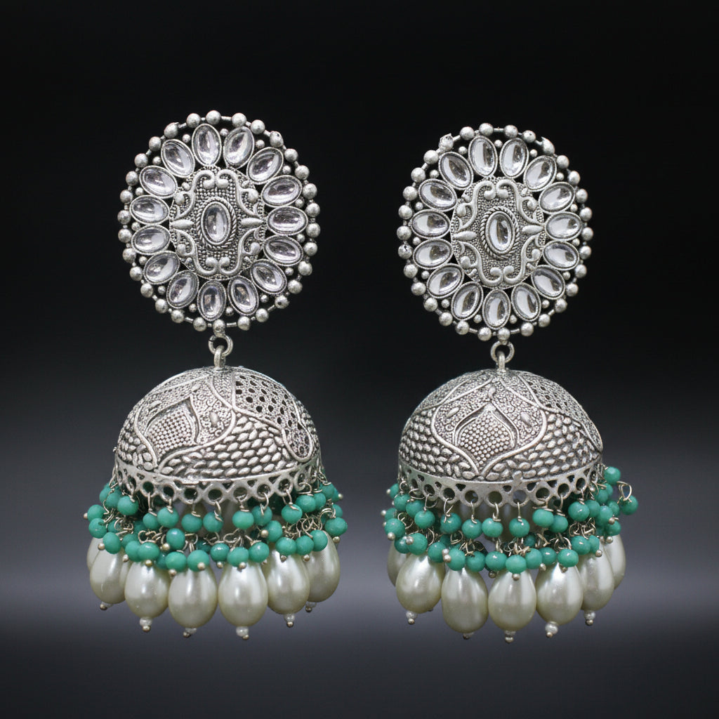 Pair of silver jhumka earrings with turquoise beads and pearls on a dark background
