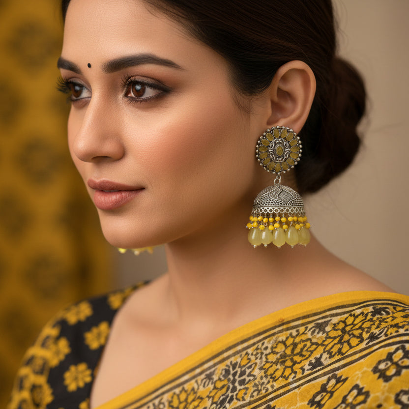 Pair of silver and yellow beaded earrings on a black background