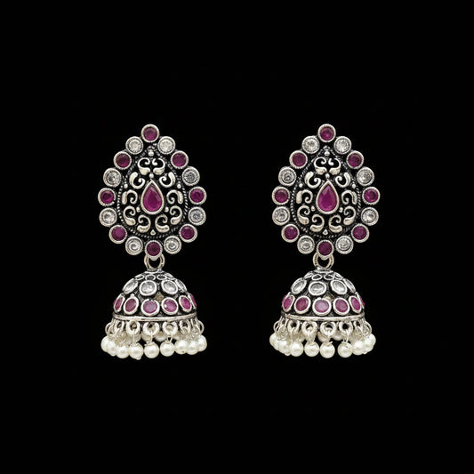 Pair of silver and pink earrings on a gray stand with 'Saheli' branding.