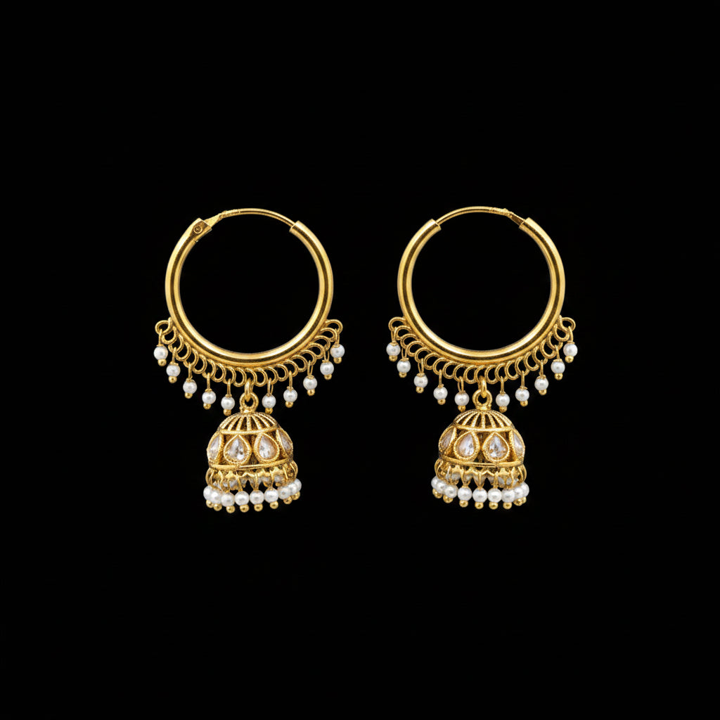 Gold earrings with pearl drops on a gray stand, branded 'Saheli'.