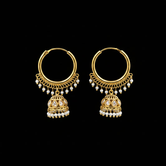 Gold earrings with pearl drops on a gray stand, branded 'Saheli'.